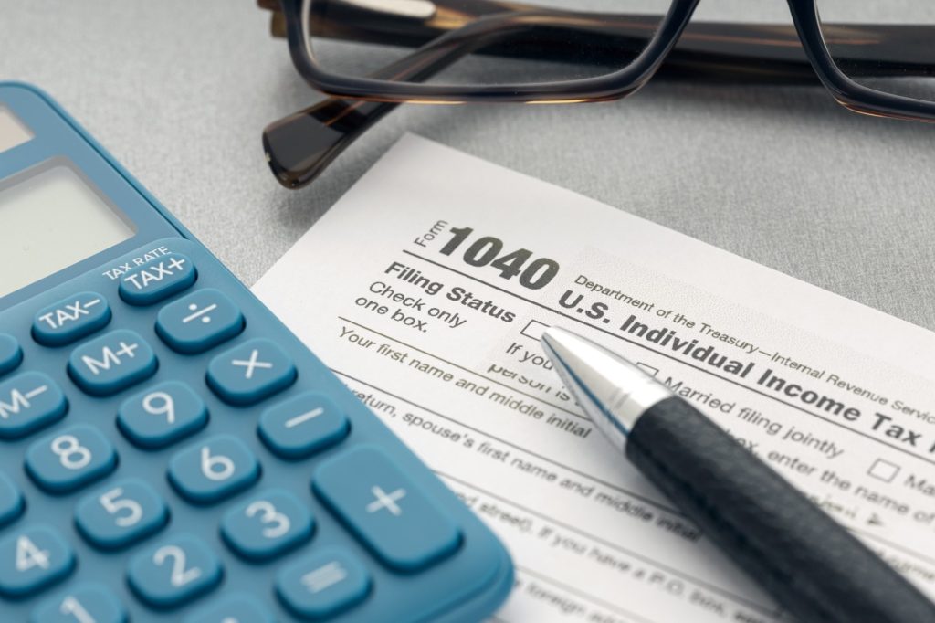 Mesa con una gafas, calculadora, bolígrafo y un documento de impuestos